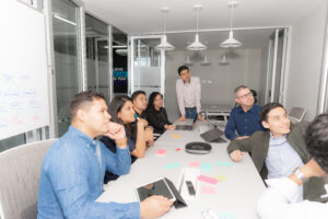 Team members in a Scrum meeting, discussing tasks and progress around a conference table.